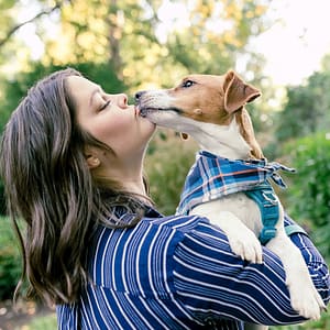 Dog trainer holding a small dog as it kisses her face